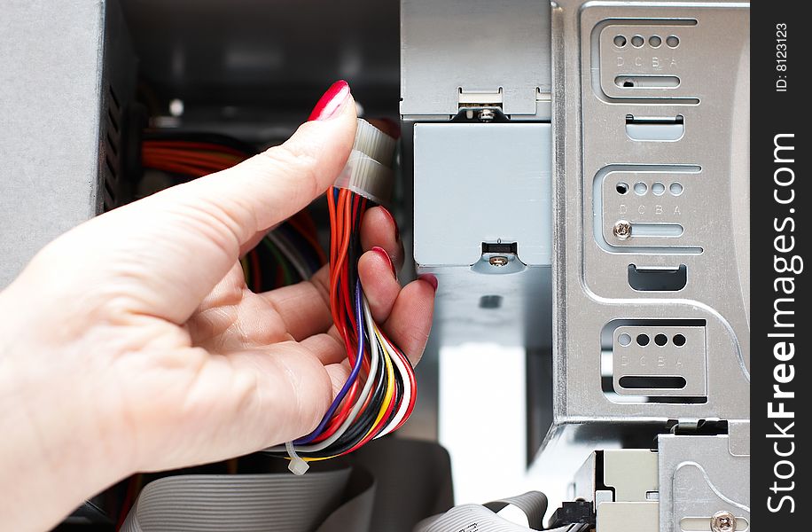 Woman hand assembles computer cable into system unit
