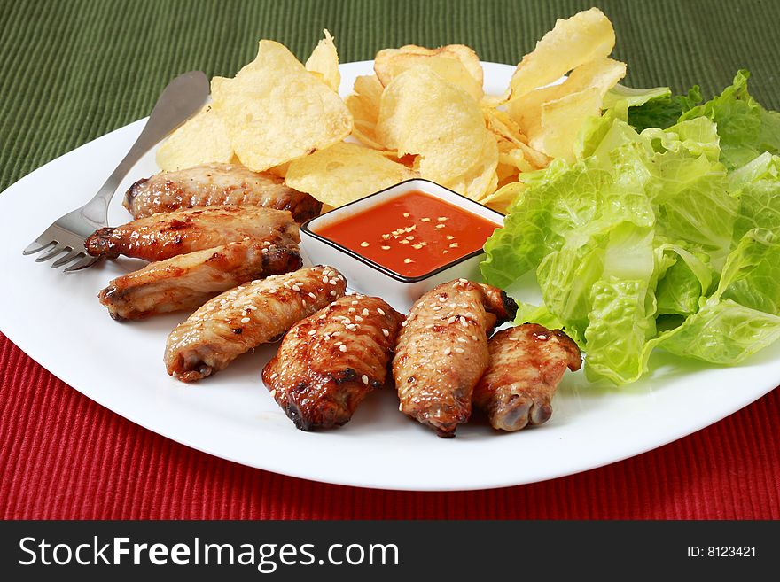 Grilled chicken wings with hot pepper sauce and salad