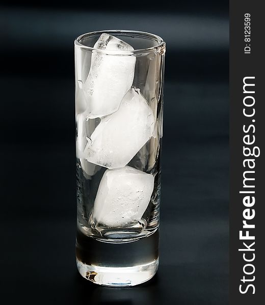 Transparent glass with ice bricks on the black background