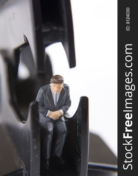 Miniature businessman sitting within a staple remover. Miniature businessman sitting within a staple remover.