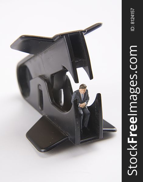 Miniature businessman sitting within a staple remover. Miniature businessman sitting within a staple remover.