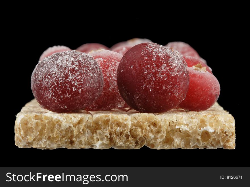 The frozen cranberry on a bread slice. A close up. The frozen cranberry on a bread slice. A close up.