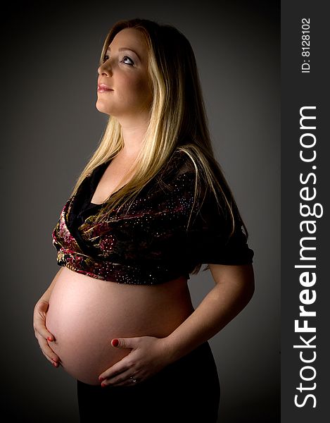 Side view of pregnant woman holding her tummy on an isolated background