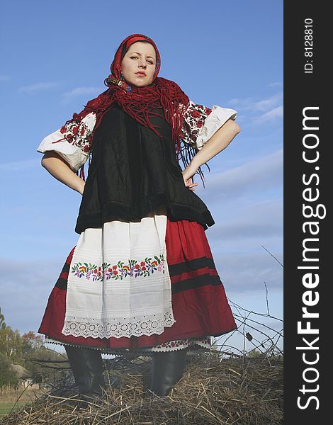 Village girl in Ukrainian clothes standing on haycock