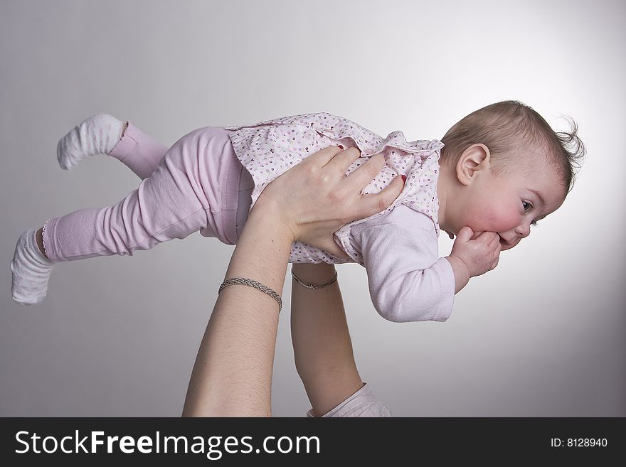 A baby hold high by his mother and looks like she is flying. A baby hold high by his mother and looks like she is flying