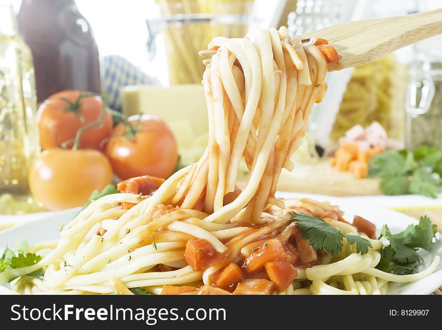 Freshly cooked spaghetti with tomato sauce on a wooden fork