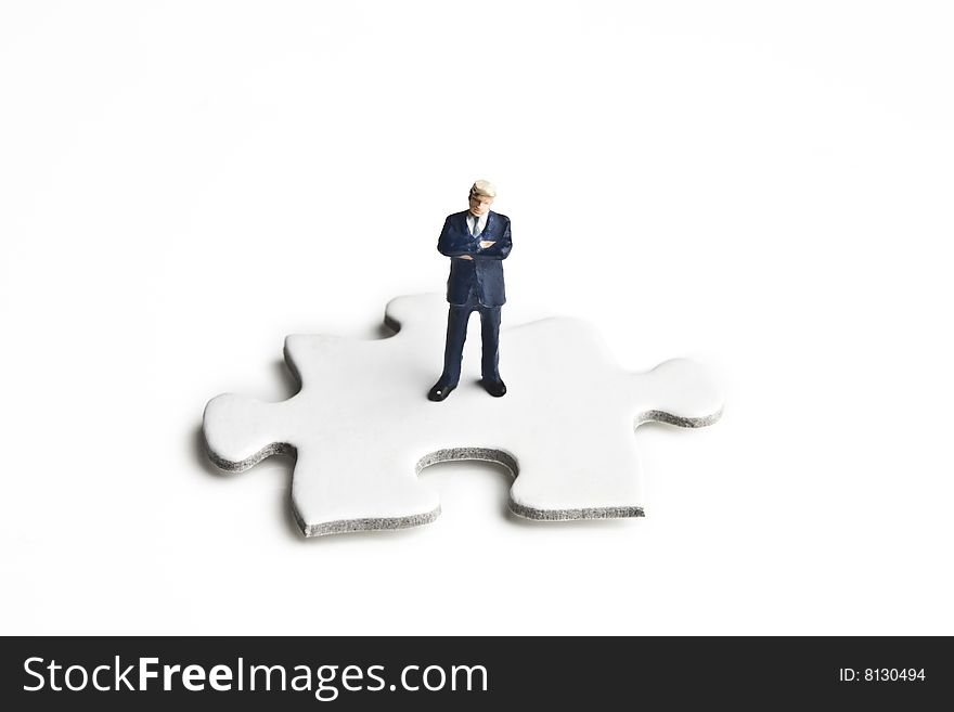 Businessman figurine placed on a puzzle piece. Businessman figurine placed on a puzzle piece