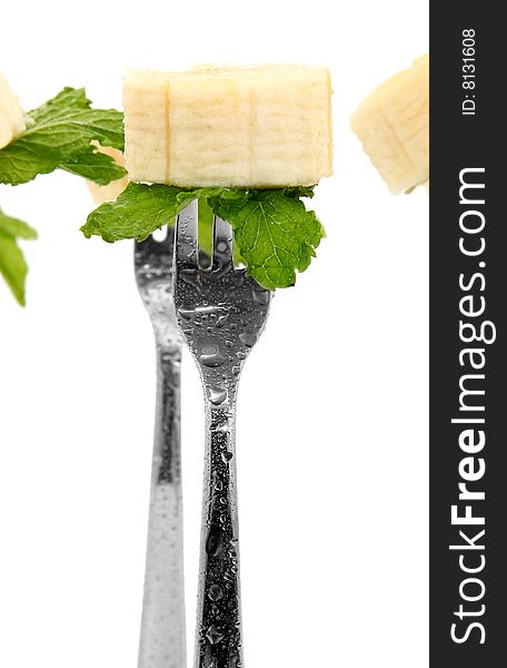 Slices of fresh banana and mint leaves on forks over white. Slices of fresh banana and mint leaves on forks over white.