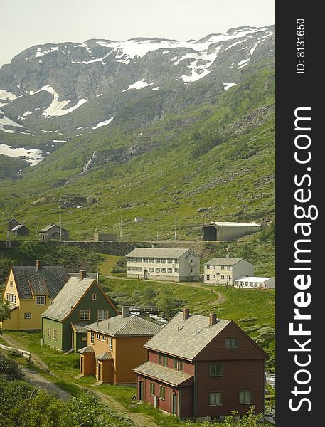 Houses in a valley in Norway with snow capped mountains in the background. Houses in a valley in Norway with snow capped mountains in the background