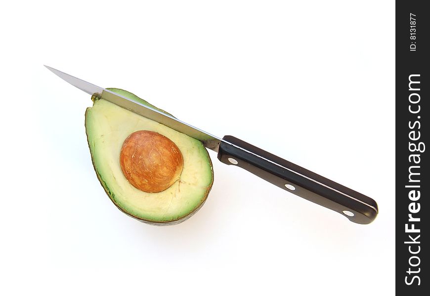 Avocado on cutting board with knife over white