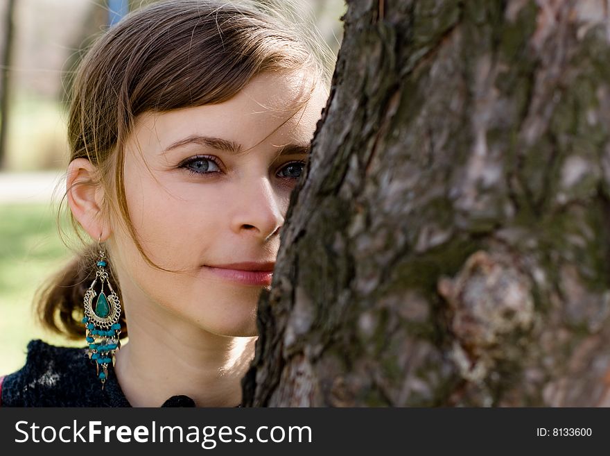 Beautiful girl hidding behind a tree outdoor. Beautiful girl hidding behind a tree outdoor