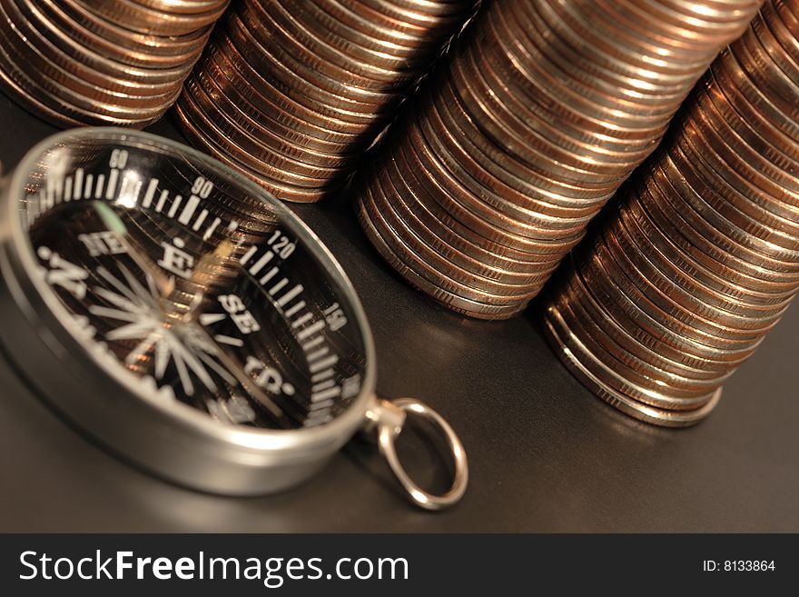 Compass lying on background with coin columns. Compass lying on background with coin columns
