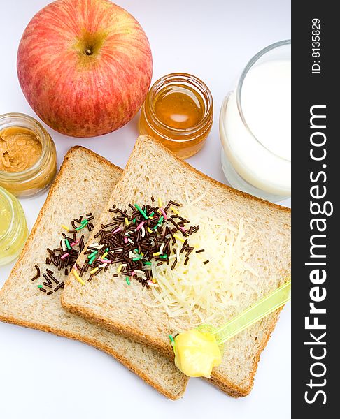 Meal ingredient for healthy & easy breakfast: wheat bread, fruit jam, chocolate sprinkles, a glass of milk, butter and apple. Meal ingredient for healthy & easy breakfast: wheat bread, fruit jam, chocolate sprinkles, a glass of milk, butter and apple