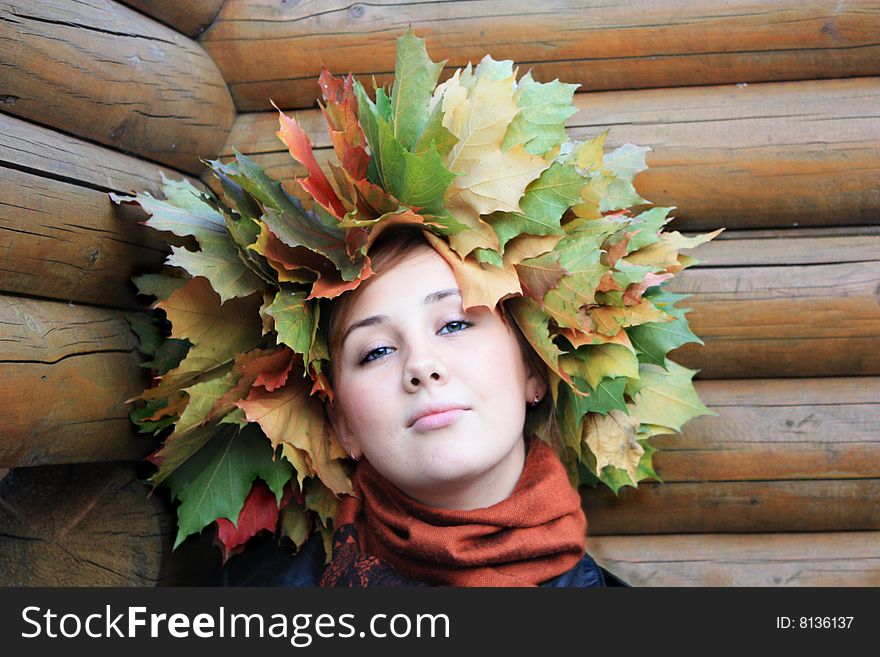 Girl with autumn yellow  leaves at the wood background