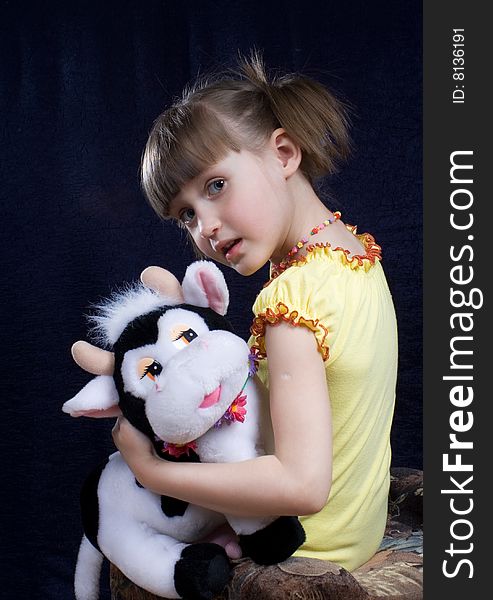 Girl sits on chair in hand toy(cow). Girl sits on chair in hand toy(cow)