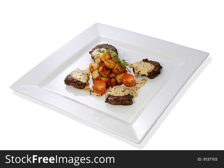 Juicy steak with mushroom sauce, roasted potatoes and cherry tomatoes on a white plate. Isolated. Juicy steak with mushroom sauce, roasted potatoes and cherry tomatoes on a white plate. Isolated.