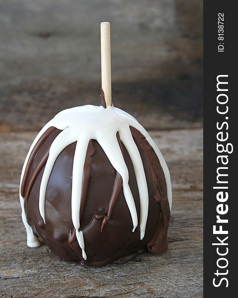An apple dipped in dark and white chocolate on a wooden background for a rustic look. An apple dipped in dark and white chocolate on a wooden background for a rustic look.