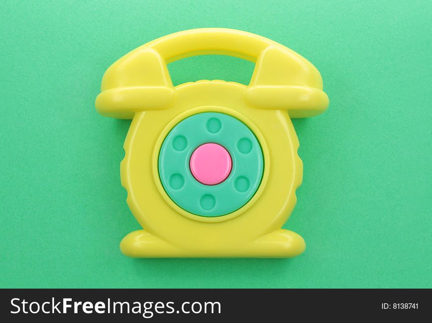 Yellow toy phone on a green background