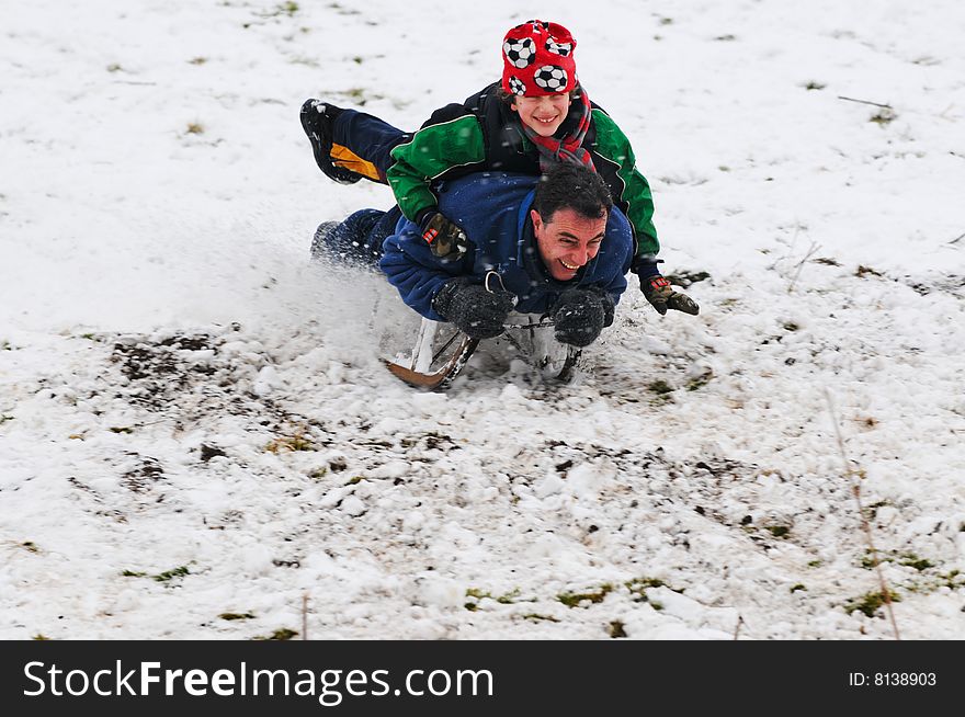 Action shot of father and son on sledge