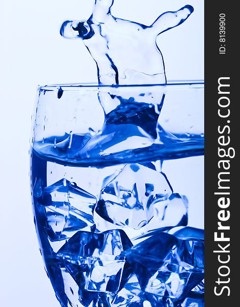 Blue Glass with Splashing water. Coolness Drink