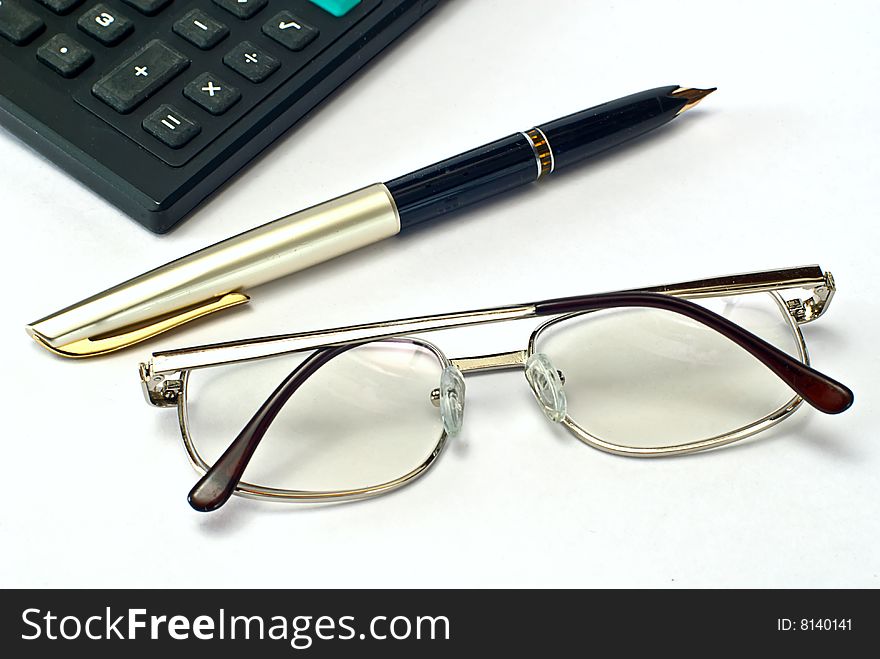 Calculator, pen and spectacles on white