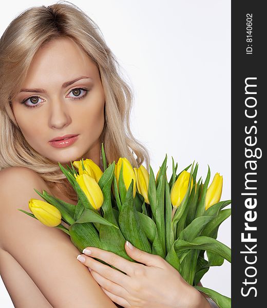 Portrait of the girl on a white background with yellow flowers tulips