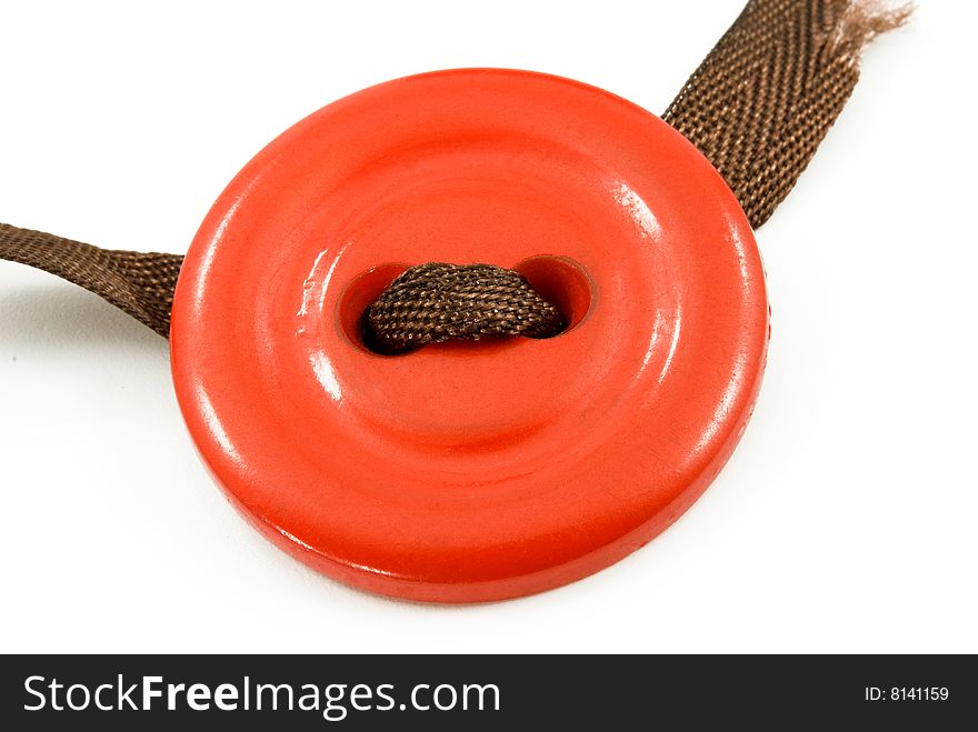 Old red button with a brown ribbon on a white background. Old red button with a brown ribbon on a white background