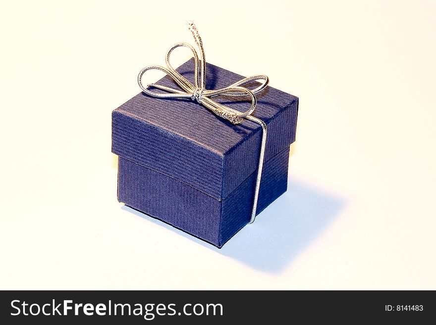 Blue GIft Box With Silver Cockade On White Background With Shadow.