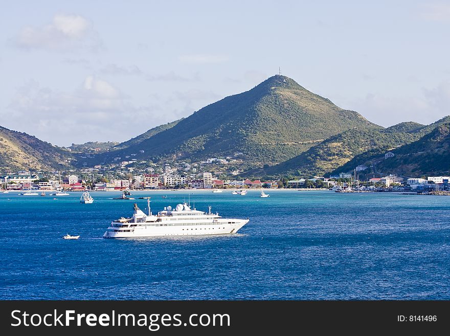 A large white yacht at anchor by a green tropical island. A large white yacht at anchor by a green tropical island