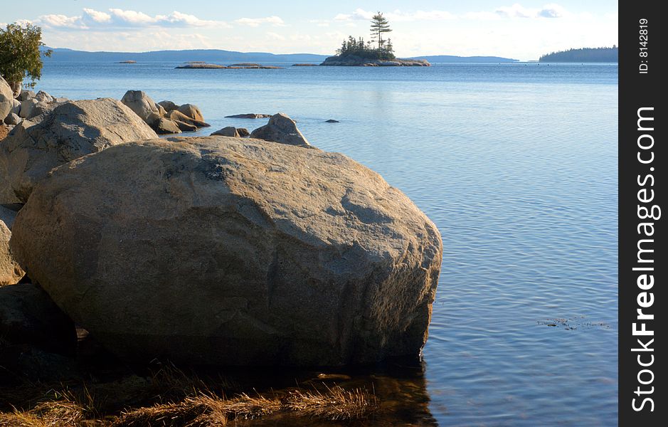 Coastal image with a large boulder in the foreground with an island in the background. Coastal image with a large boulder in the foreground with an island in the background.