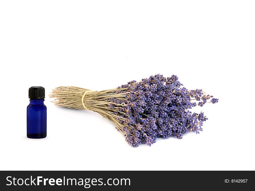 Dried lavender herb flowers with blue essential oil glass bottle over white background.