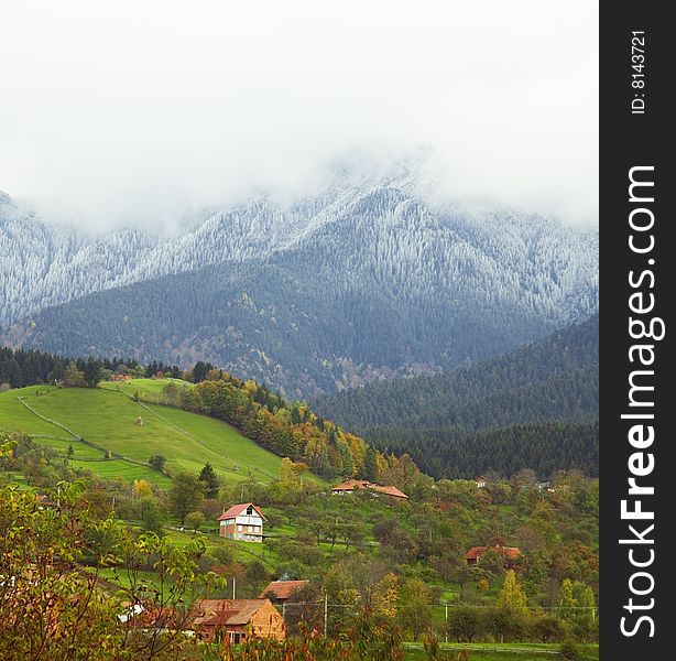Scenic landscape of a mountain village in fall, with first snow in the woods