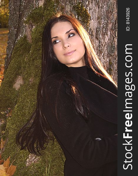 Beautiful young woman sitting near tree