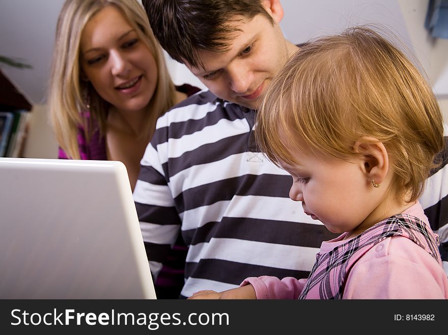 Little girl with parents play wit a white laptop computer. Little girl with parents play wit a white laptop computer