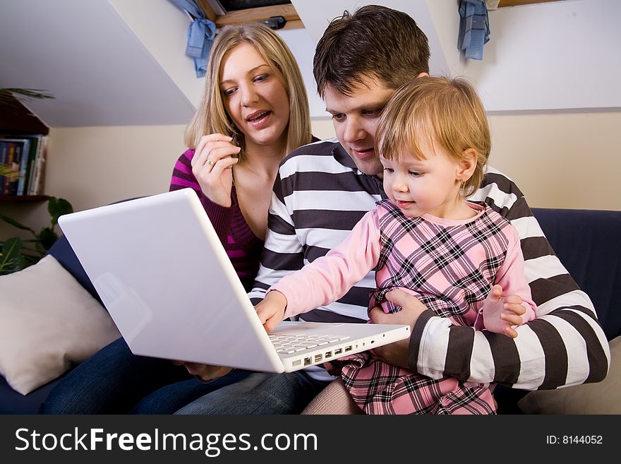 Little girl with parents play wit a white laptop compute. Little girl with parents play wit a white laptop compute