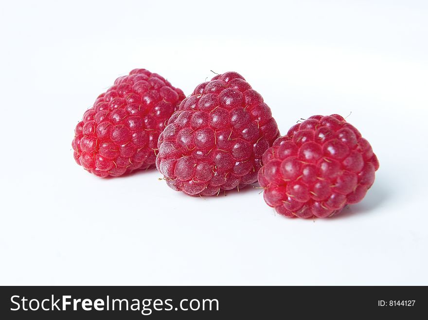 Closeup of three raspberries on white background