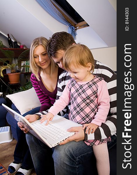 Little girl with parents play with a laptop