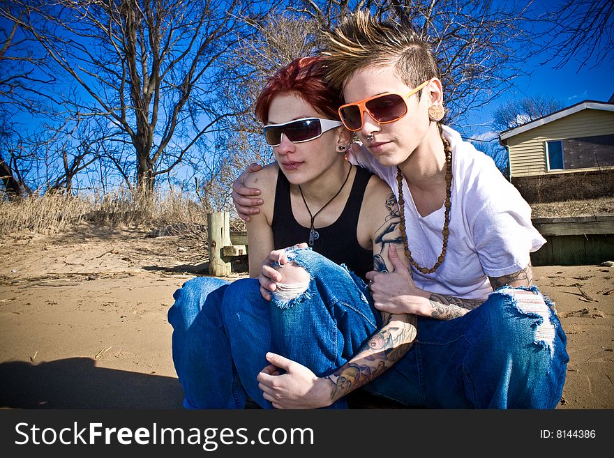 Two young women crouching on the beach