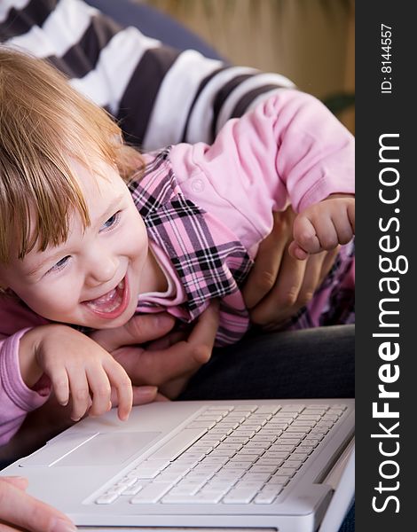 Beutiful little girl play with white laptop computer. Beutiful little girl play with white laptop computer