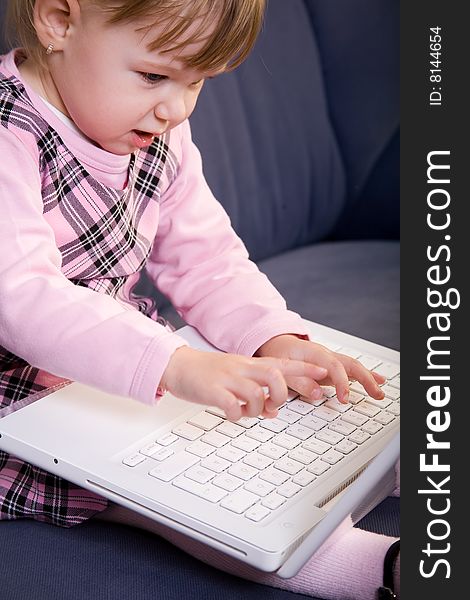 Beutiful little girl play with white laptop computer. Beutiful little girl play with white laptop computer