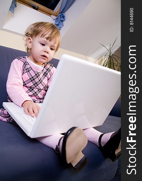 Beutiful little girl play with white laptop computer. Beutiful little girl play with white laptop computer