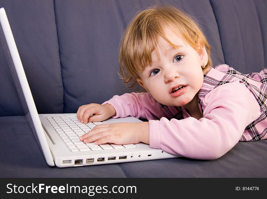 Beutiful little girl play with white laptop computer. Beutiful little girl play with white laptop computer