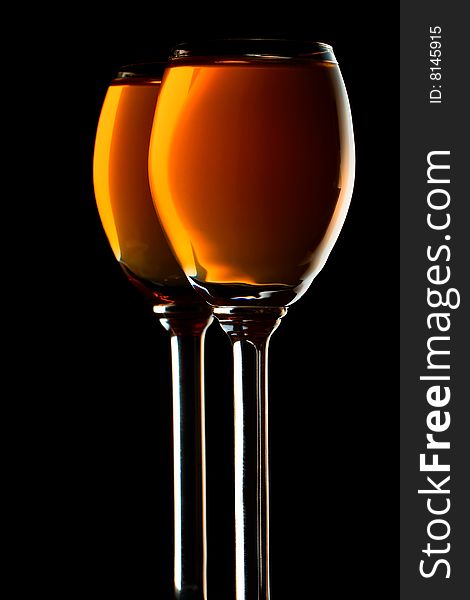 Two small glasses filled with orange liquor on black background. Two small glasses filled with orange liquor on black background