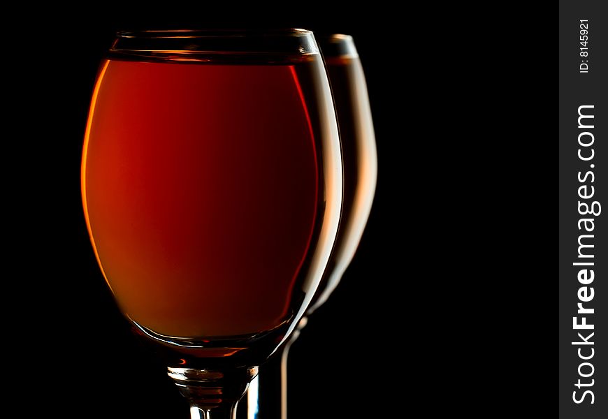 Two small glasses filled with orange liquor on black background. Two small glasses filled with orange liquor on black background
