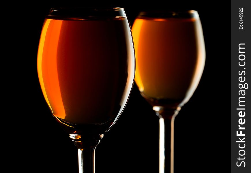 Small glasses filled with orange liquor on black background. Small glasses filled with orange liquor on black background