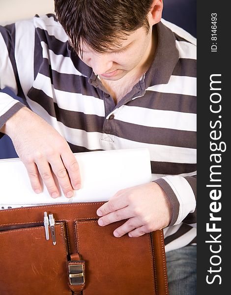 Young man put a white laptop computer into the bag. Young man put a white laptop computer into the bag