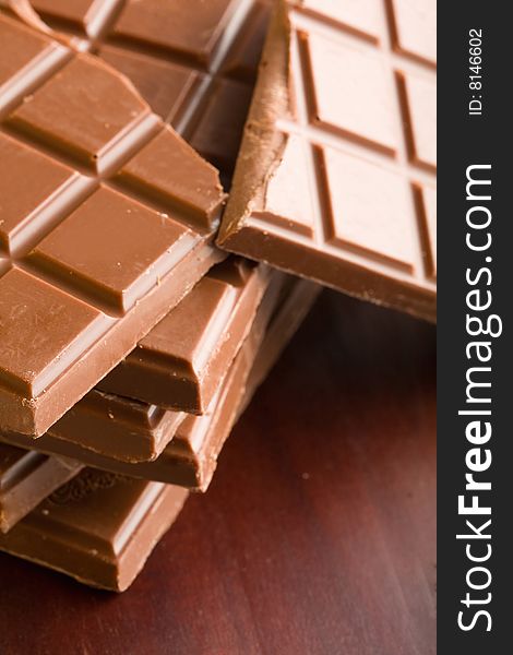 Milk chocolate with great sheen presented on rich wood. Milk chocolate with great sheen presented on rich wood