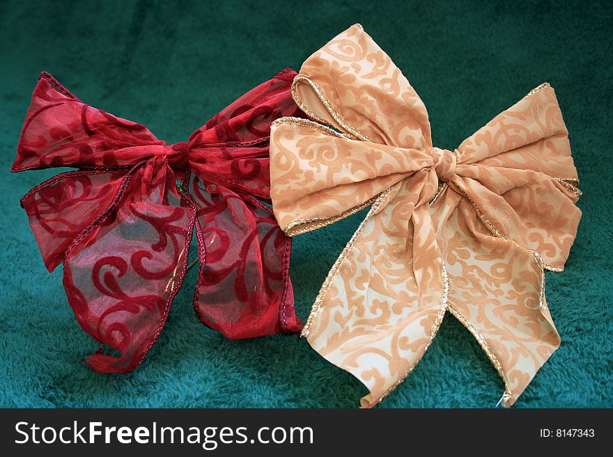 A set of fancy bows. One is red and the other is gold in color.