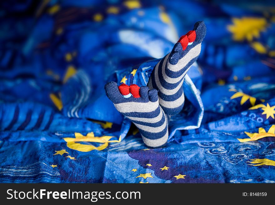 Stock photo: an image of little girl's feet in striped socks on a bed. Stock photo: an image of little girl's feet in striped socks on a bed