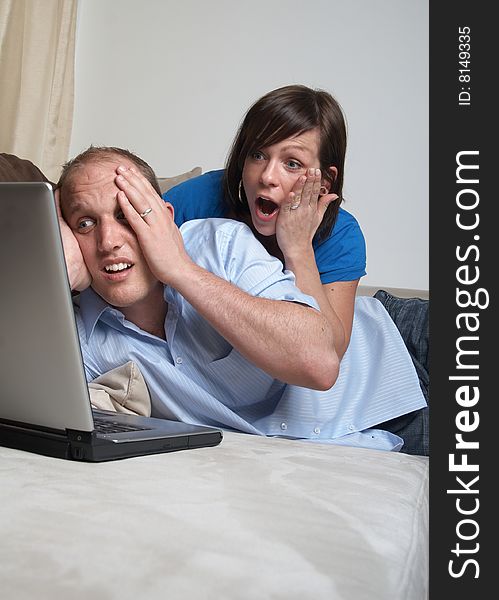 Young couple on the couch at home looking at the laptop!. Young couple on the couch at home looking at the laptop!